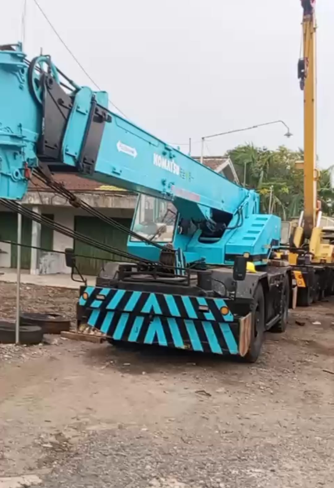 Rough terrain crane Komatsu biru tampak depan di area pool unit