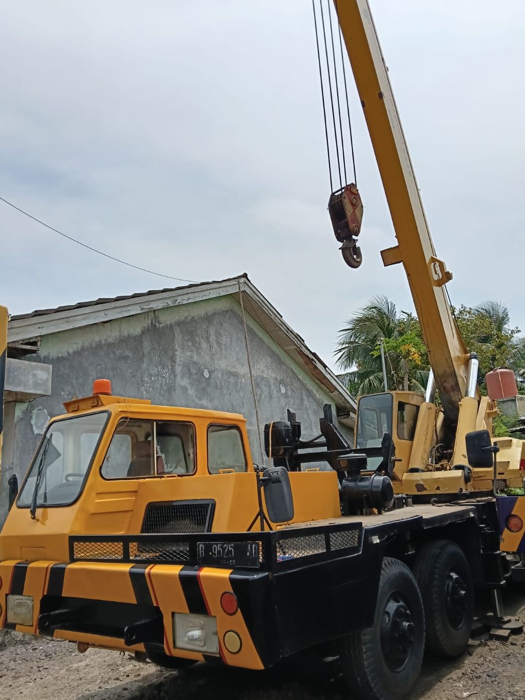 Mobile crane kuning dengan boom terangkat dan hook siap kerja