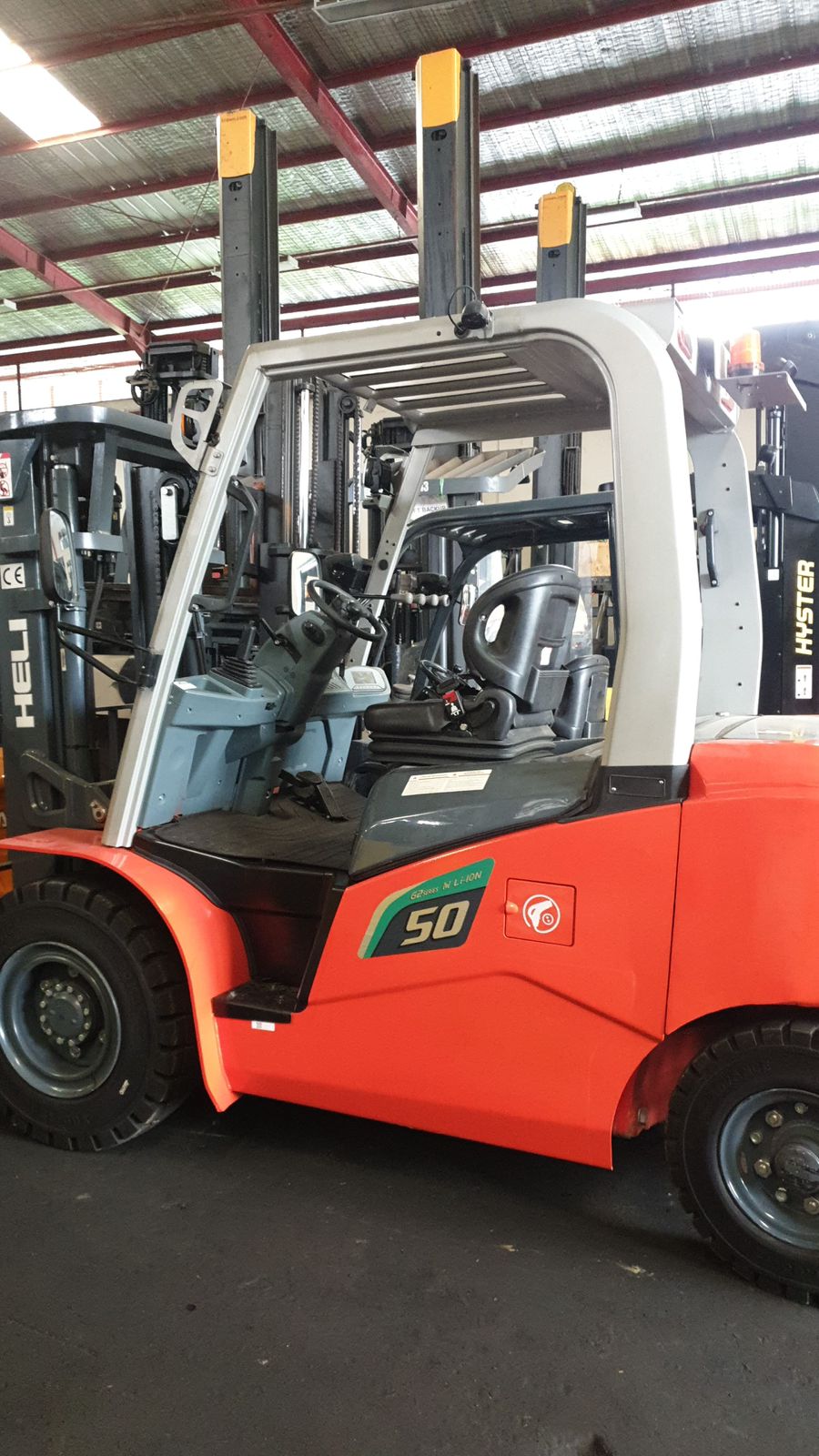 Forklift merah dengan sudut samping di gudang indoor